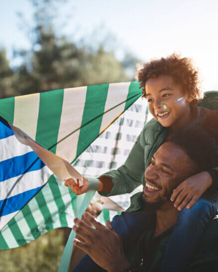 Father and son having fun flying kite on sunny day